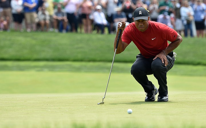 Tiger Woods makes sure he has the line on his birdie putt on No. 5.